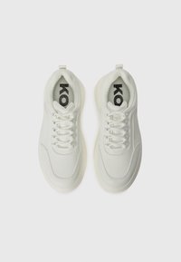 Hvite sneakers med en glatt syntetisk overdel, polstret krage, snøring og en teksturert innersåle med en logo. Yttersålen er litt gjennomsiktig.