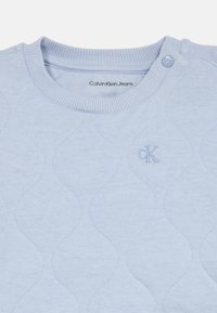 Ανοιχτό μπλε πλεκτό πουλόβερ Calvin Klein Jeans με κουμπωτό λαιμό, διακριτό �διαμαντένιο σχέδιο και μικρό κεντημένο λογότυπο "cK".