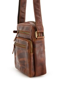 Brun læder crossbody taske med flere lynlåslommer, robust skulderrem og guldfarvet hardware; glat tekstur og rektangulær form.