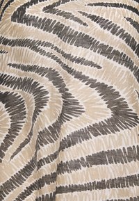 Motif textile abstrait avec des rayures irrégulières, dessinées à la main, de couleur beige et brun foncé créant un design tourbillonnant et dynamique sur le tissu.
