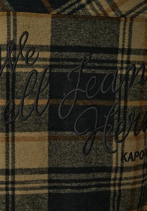 Tissu à carreaux dans des teintes de noir, marron et jaune avec du texte brodé "Nous allons Jean ici" en fil foncé, présentant de fins détails.