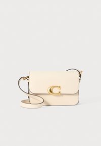 Borsa a tracolla in pelle crema con logo "C" dorato, design piatto e texture liscia. Presenta una tracolla rimovibile e bordi neri.