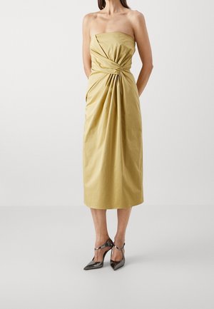 Robe midi jaune pâle sans bretelles avec un détail noué froncé à la taille, portée avec des escarpins métalliques à bouts pointus.