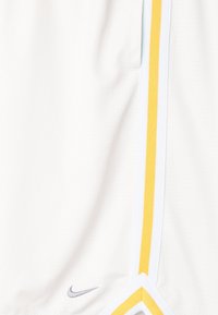 Shorts de sport blancs avec des rayures verticales jaunes et un petit logo Nike gris près de l'ourlet.