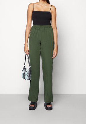 Zelené, lehké kalhoty s širokými nohavicemi a elastickým pasem. Kombinovány s černým topem na tenká ramínka a černými robustními sandály na platformě.