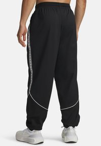 Black jogger pants with an elastic waistband, white side stripes, and curved panel accents. Made from a lightweight, breathable material.