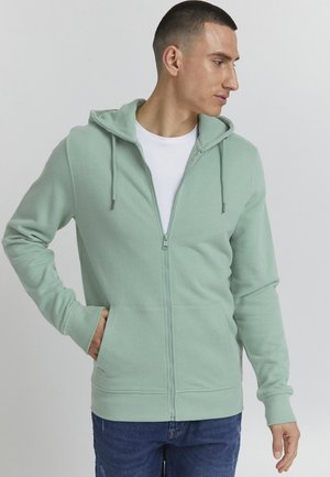 Mintgrøn zip-op hoodie med en snoretrækshætte, forlommer og ribbede manchetter. Fremstillet af blødt, tekstureret stof.