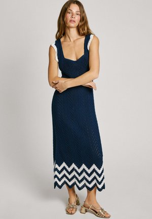 Navy knitted maxi dress with chevron white hem, featuring a scoop neck, textured pattern, and lace-trimmed shoulder straps.