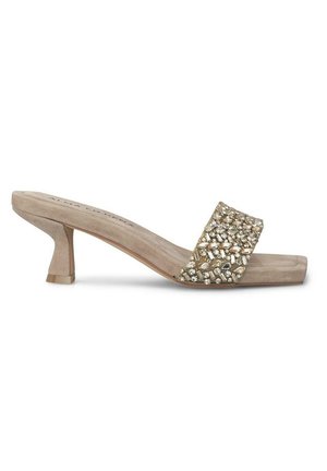 Sandales à talons en daim beige avec une large sangle ornée de pierres décoratives transparentes et dorées. Design de talon bloc, avant plat.