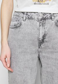 Högmidjade grå denimjeans med en blekt tvätt, framfickor, bälteshörn och en knappstängning. Texturerad tyg och ren design.