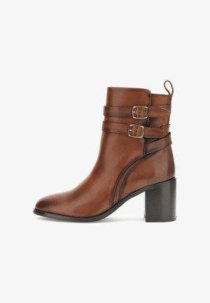 Bruine leren enkelboot met een ronde neus, twee verstelbare zilveren gespbanden en een middenhoog zwarte blokhak. Glad textuurafwerking.