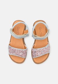 Glittriga rosa sandaler med ett mjukt blått justerbart band; läderinan och dekorativ sömnad runt sulan. Slät textur överlag.