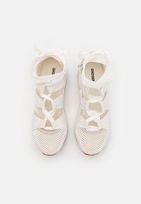 White shoes with a mesh upper, crisscross ribbon laces, and perforated toe caps. Smooth texture with circular pattern accents.