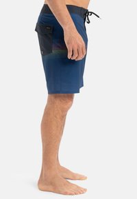 Shorts de bain pour hommes en bleu marine avec des rayures dégradées horizontales, dotés d'une poche à rabat noire et d'un cordon de serrage. Tissu léger et à séchage rapide.