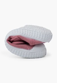 Zapatilla blanca sin cordones con suela de goma texturizada, que presenta un interior de tela rosa plegado. La zapatilla tiene una forma redondeada y un diseño acolchado.