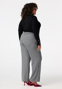 Zwarte langemouwen top, grijs gestreepte wijde broek, achterkantzicht, met een rechte pasvorm, zakken en rode hakken. Textuurdetails van de stof zichtbaar.