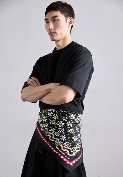 Black floral bandana with white daisies and colored accents, made of smooth fabric, worn around the waist, featuring the brand name "Moschino."