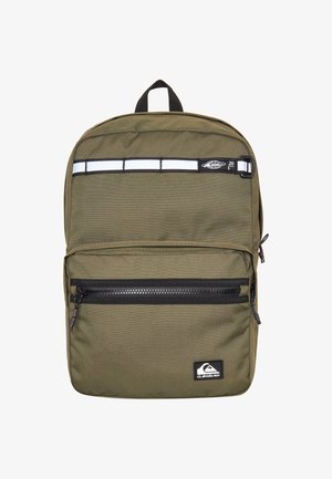 Sac à dos vert olive en tissu lisse, avec une poche zippée à l'avant, une bande réfléchissante et des accents noirs ; logo affiché à l'avant.
