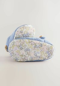 Blå denimskor med blommönstrad sula. Har rundad form, knappdetalj och mjuk textur. Sulan är ljus med pastellfärgade blommor.