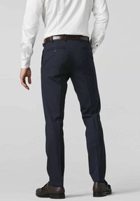 Marineblauwe broek van gladde stof, met een slim fit, riemlussen en twee achterzakken. Gecombineerd met donkere, geweven schoenen.