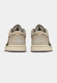 Χαμηλοτάκουνες αθλητικές μπότες σε ανοικτό μπεζ και καφέ αποχρώσεις, με υφή στην επιφάνεια, επενδεδυμένο γιακά και μια ελαφρώς ριγέ μπεζ ενδιάμεση σόλα με λογότυπο στη φτέρνα.