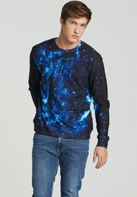 Black sweatshirt with a blue galaxy print and stars, featuring long sleeves and a round neckline. Worn with blue denim jeans.