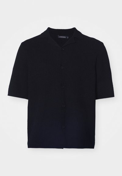 Lyhythihainen musta nappipaita teksturoidusta kankaasta, jossa on leirikaulus ja kuusi vastaavaa nappia edessä.