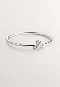 Anillo de plata con una banda delgada, que presenta tres pequeñas piedras redondas transparentes dispuestas en un diseño de racimo. Superficie suave con un acabado pulido.