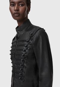 Zwarte leren jack met een hoge kraag, complexe knopen detail en een getailleerde snit met schouderaccenten.