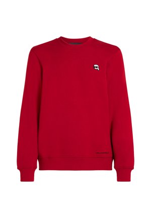 Sudadera roja hecha de material suave, con cuello redondo, puños acanalados y un pequeño logotipo en el pecho. Diseño clásico, corte relajado.