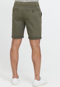 Shorts vert olive avec revers, fabriqués dans un tissu doux. Dotés de deux poches arrière avec des boutons et d'un design à l'avant plat.