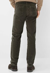 Donkergroene corduroy broek met een rechte snit, voorzien van achterzakken en een getextureerd oppervlak. Gecombineerd met donkerbruine schoenen.
