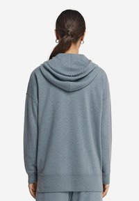 Przesadny hoodie z miękkiej, jasnoniebieskiej tkaniny, z kapturem na sznurku, ribbowymi mankietami i dołem, charakteryzujący się luźnym krojem i minimalistycznym wzornictwem.