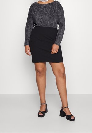 Černá mini sukně v kombinaci s metalickým topem s dlouhým rukávem. Top má třpytivou texturu, zatímco sukně je jednobarevná černá a přiléhavá. Černé sandály na blokovém podpatku dokončují outfit.