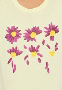 Jasnożółta koszula z fioletowymi stokrotkami o żółtych środkach, nadrukowana w prosty wzór, z szerokim dekoltem i miękką fakturą.