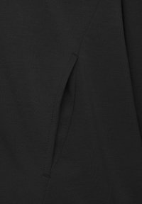 Tessuto nero con una consistenza liscia, caratterizzato da una cucitura verticale e un'apertura di tasca angolata piccola sul lato.