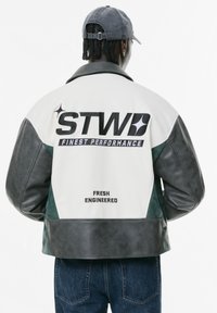 Giubbotto in pelle con corpo bianco e maniche grigio scuro, con dettagli verdi. Include testo audace e dettagli del marchio sul retro.