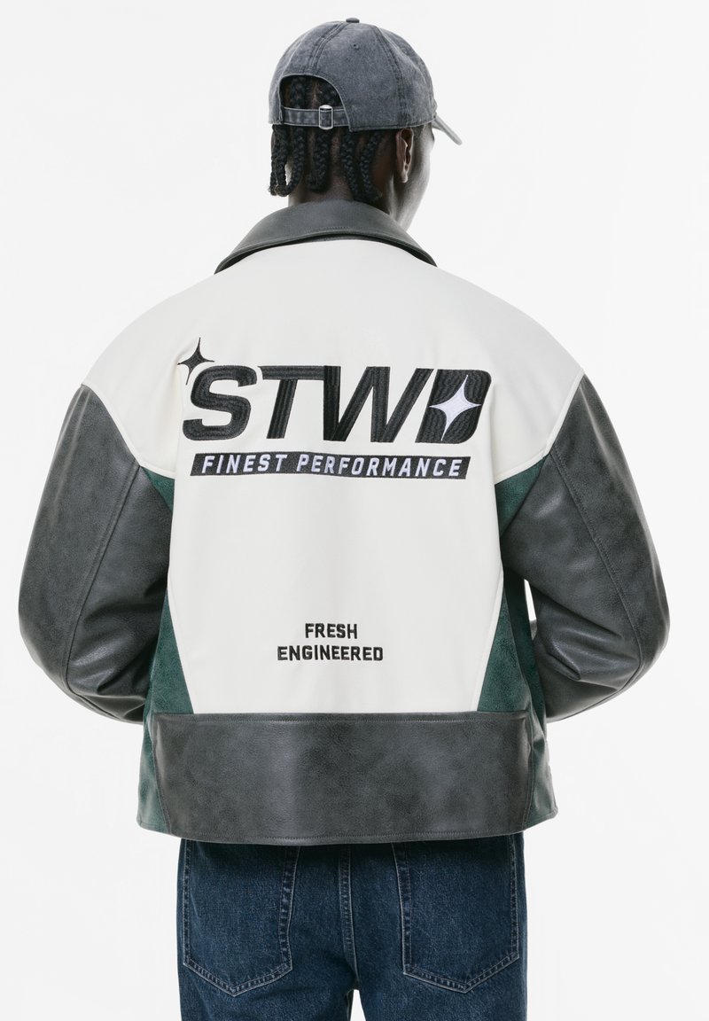 Giubbotto in pelle con corpo bianco e maniche grigio scuro, con dettagli verdi. Include testo audace e dettagli del marchio sul retro.