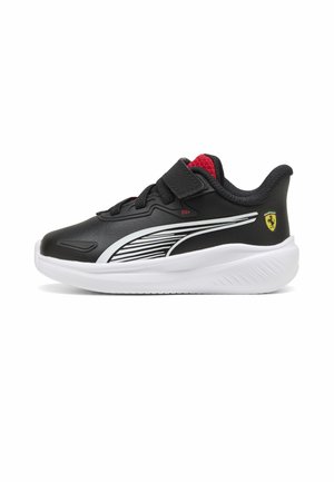 Baskets enfant noir et blanc avec doublure intérieure rouge, bride Velcro, logo Puma sur le côté et blason Ferrari sur le talon, sur fond blanc.