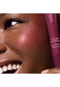 Estee Lauder Futurist Blush in een tube, met een diepe bessen tint, een zachte textuur en een glanzende finish op de wang van een model.