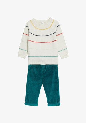 Sweter dzianinowy w kolorze kremowym z wielokolorowymi paskami, w połączeniu z turkusowymi spodniami z kordurowej tkaniny, mającymi zrolowane mankiety i miękką fakturę.