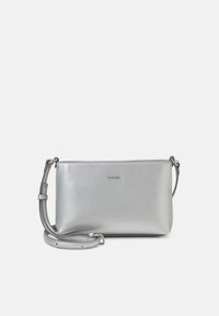 Srebrna torebka typu crossbody ze skóry z gładką teksturą, zamknięciem na zamek i regulowanym paskiem. Posiada subtelne logo z przodu.