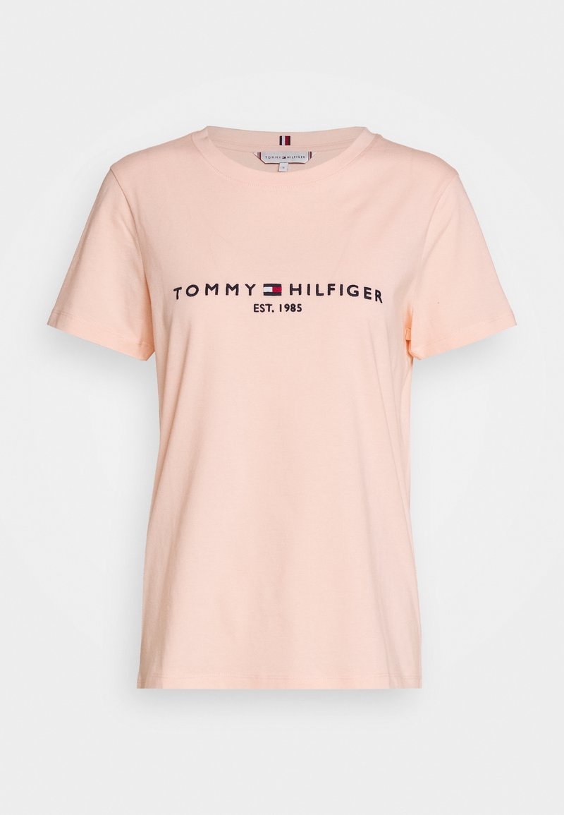 Peachfarvet bomulds T-shirt med korte ærmer. Har "TOMMY HILFIGER EST. 1985" logo i marineblå med et rødt og hvidt emblem.