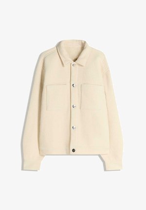 Jachetă din catifea de tip cord, de culoare crem, cu guler, două buzunare la piept, nasturi capse argintii și textură reiată. Are un design ușor cropped.