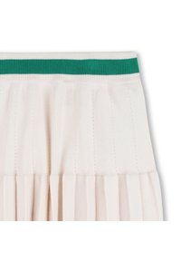 Λευκή πλισέ φούστα με πράσινη κορδέλα μέσης ριπ. Διαθέτει κάθετη ριπ και μαλακή υφή, τονίζοντας ομοιόμορφες πτυχώσεις σε όλη την επιφάνεια.