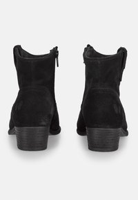 Botines de ante negro que presentan un tacón bajo, cremalleras traseras y una textura suave, con un simple pespunte a lo largo de las costuras.
