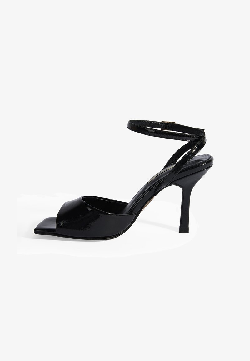 Sandale à talons hauts en cuir verni noir avec un bout ouvert, sangle cheville réglable et un design élégant et courbé.