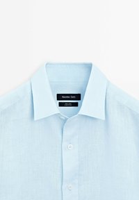 Lichtblauwe linnen shirt met een klassieke kraag, sluiting met knopen aan de voorkant en een gestructureerde stof. Etiket zegt "Massimo Dutti, 100% Linnen."