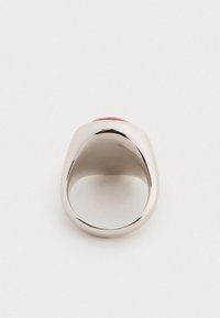 Inel metalic cu un band argintiu neted și rotunjit, având un accent roșu domat în partea de sus. Suprafață lustruită, cu o deschidere largă pentru deget.