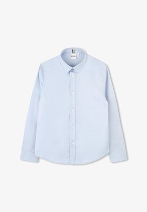 Camisa de manga longa azul clara, feita de algodão, com colarinho pontudo, frente com botões e um discreto bordado de logotipo no peito.